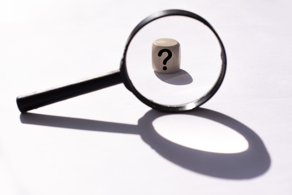 Magnifying glass with wooden block and question mark representing FAQs 