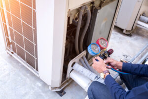 Technician working on air conditioning unit for heating and AC repair.